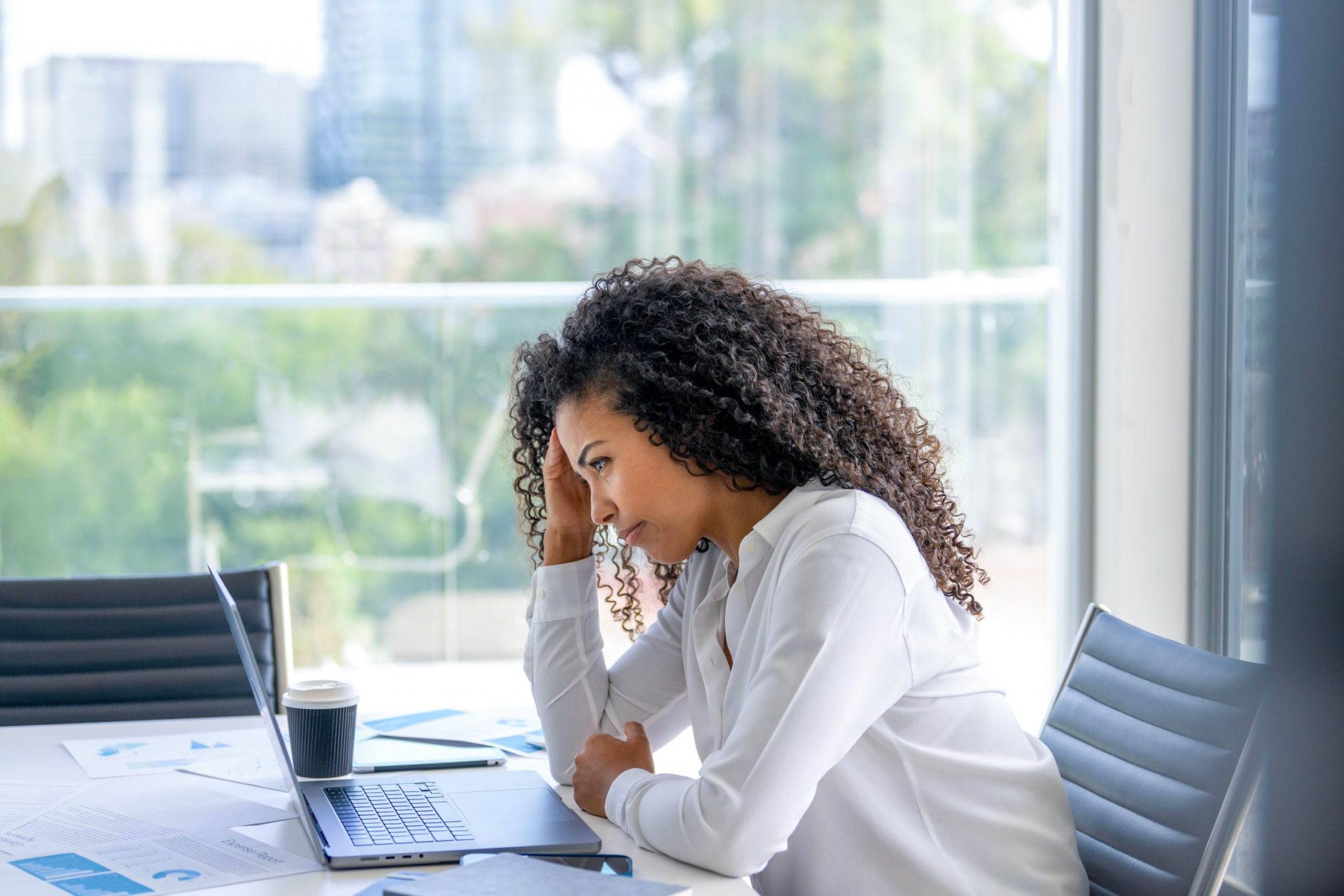 Upset woman working on a laptop computer in the office. She looks worried, frustrated and depressed