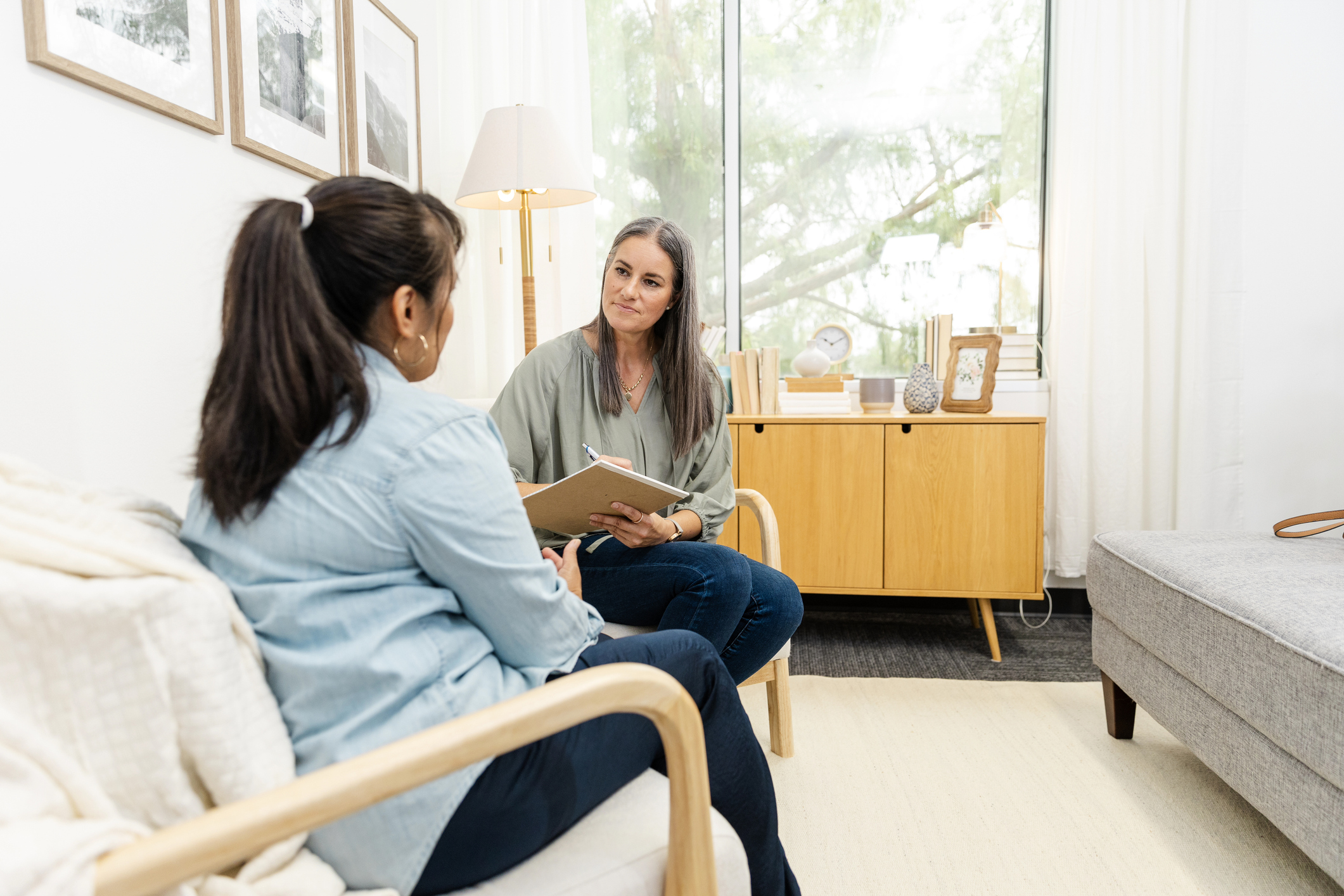 In therapist's office, woman shares and counselor takes notes
